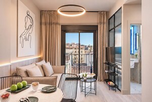 Una sala moderna con sofá, mesa de comedor y balcón con vista a la ciudad.