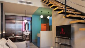 A modern living room with a sofa, coffee table, and a TV displaying the Netflix logo. - Coeo Peña Design Apartments (Málaga)
