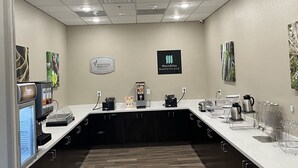 A modern breakfast area with a long counter, coffee machines, and a sign for MainStay Marketplace. - MainStay Suites Dallas Northwest - Irving (Dallas)