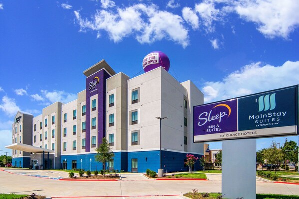 A Sleep Inn & Suites hotel with a blue and white exterior, a large signboard, and a clear sky. - MainStay Suites Dallas Northwest - Irving (Dallas)