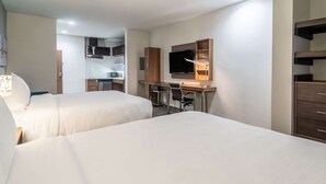 A hotel room with two beds, a desk with a chair, a TV, and a kitchenette. - MainStay Suites Dallas Northwest - Irving (Dallas)