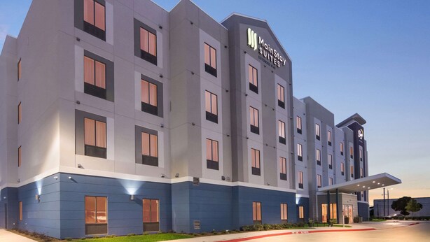 A modern hotel building with a prominent 'MainStay Suites' sign, multiple windows, and a covered entrance area. - MainStay Suites Dallas Northwest - Irving (Dallas)