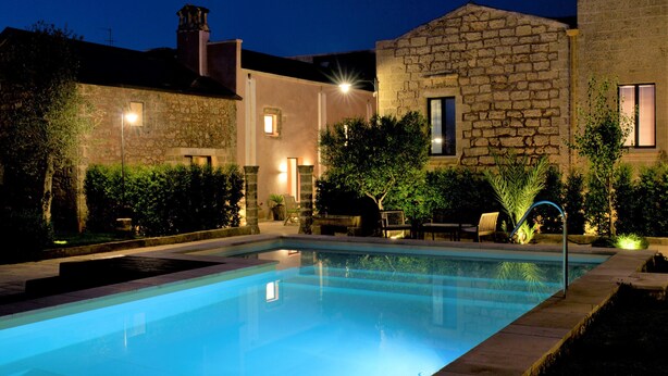 Une piscine avec un bâtiment en pierre en arrière-plan.