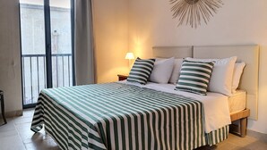 Une chambre d’hôtel avec un lit, une table de chevet, une lampe, un élément de décoration murale et une vue sur l’extérieur.