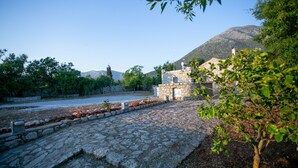 Un camí de pedra que porta a un edifici de pedra, amb una muntanya al fons.