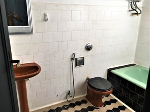 A bathroom with white tiled walls, a brown toilet, a green bathtub, and a brown sink. - Hostel Bella Ciao (Rio de Janeiro)
