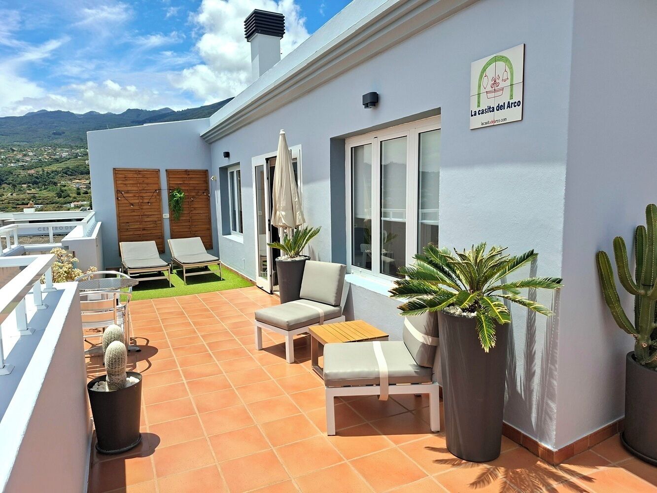 Eine Dachterrasse mit Außenmöbeln, Topfpflanzen und Blick auf die Landschaft.