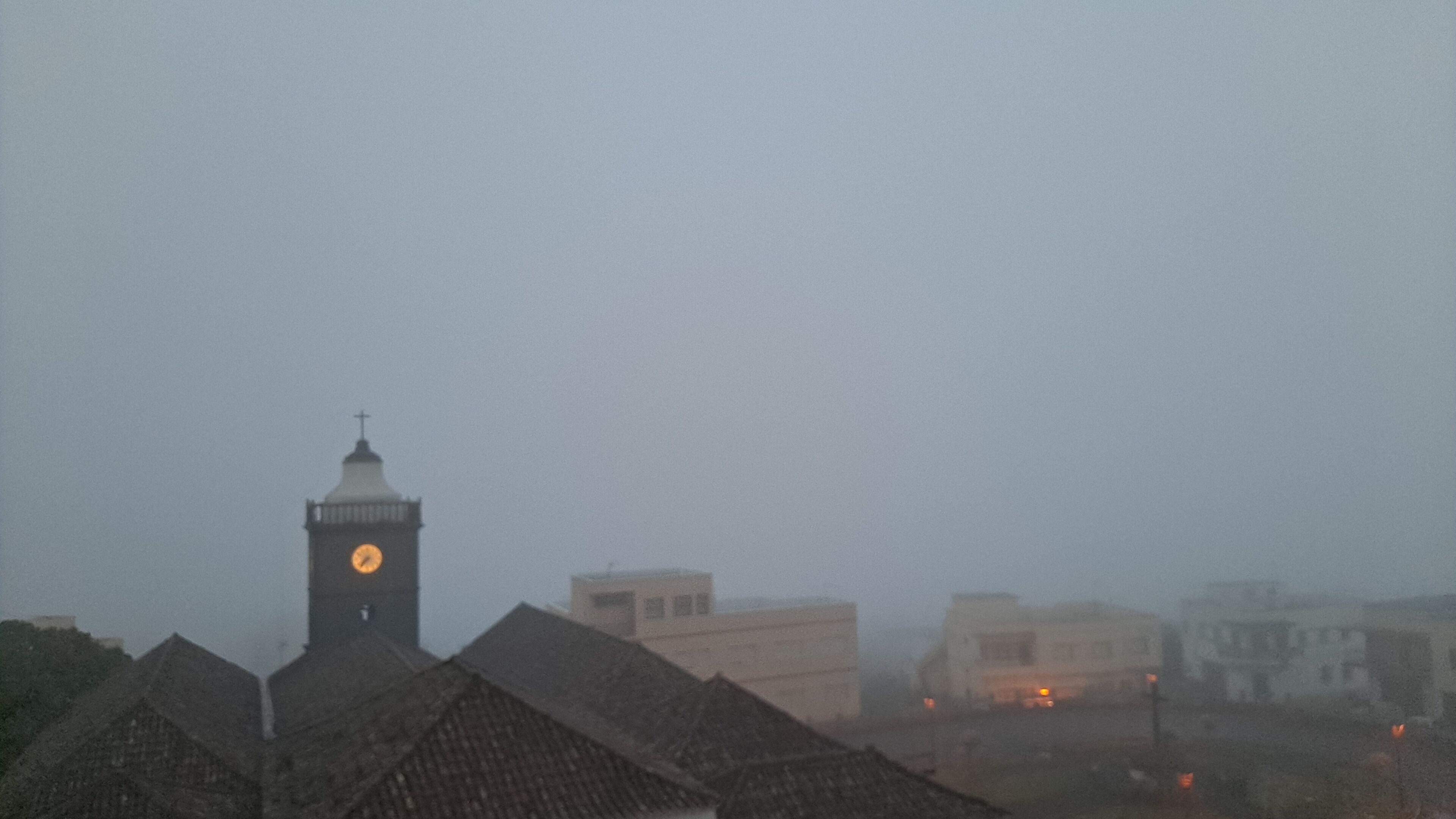 A foggy cityscape with a prominent clock tower and several buildings.