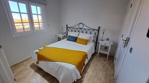 Une chambre à coucher avec un lit, deux tables de chevet, une fenêtre et une porte.