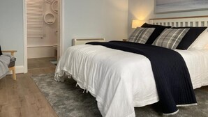 A bedroom with a bed, a nightstand, a lamp, and a painting on the wall. - Relax by the Sea (Weymouth)
