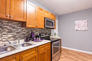 Una cocina con armarios de madera, un fregadero de acero inoxidable, un microondas y un horno.