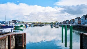 Un port de plaisance avec des bateaux amarrés, un pont et des bâtiments le long de la rive.