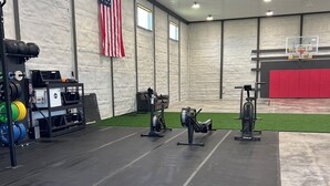 Une salle de sport équipée de matériel de musculation, d’un panier de basket et arborant un drapeau américain.