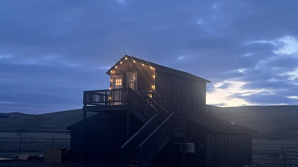 Une cabane en bois dotée d’un balcon et d’un escalier menant à un deuxième étage.