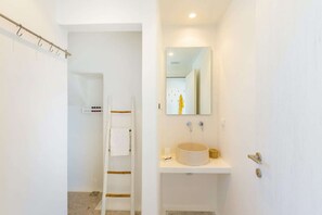 A bathroom with a white sink, a mirror, and a towel rack.