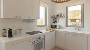 Una cocina moderna con armarios blancos, horno empotrado, microondas y un amplio ventanal con vistas al exterior.