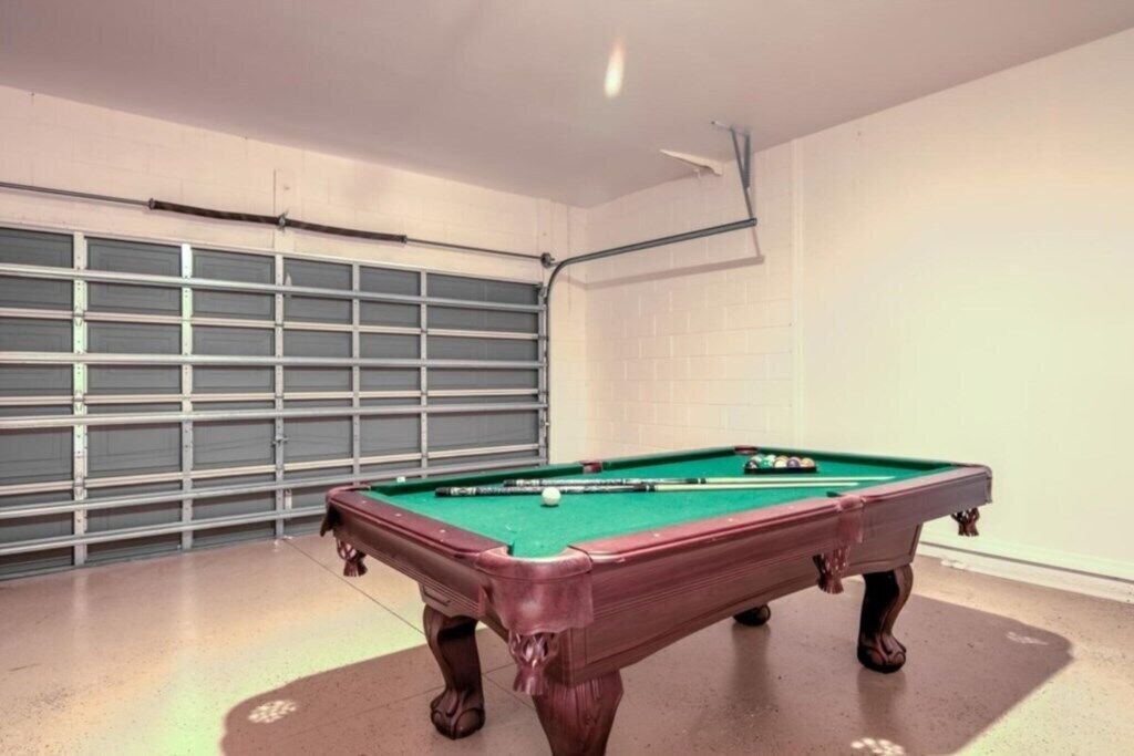 Taula de bitlles en una habitació amb porta garatge i parets de rajola.