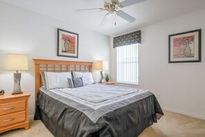 A bedroom with a bed, two bedside tables, a ceiling fan, and two framed artworks on the walls. - Beautiful Disney's pool villa (Davenport)