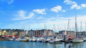 Een jachthaven met diverse boten afgemeerd, een heldere lucht en gebouwen op de achtergrond.