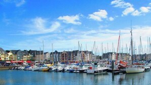 A marina with numerous boats docked, a clear sky, and buildings in the background. - Maison 2 Chambres Proche Commerces à Louer Pour les Vacances (ARZON)