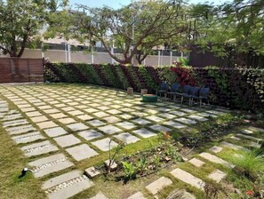 Relax in a serene outdoor space with a checkered patio surrounded by lush greenery and comfortable seating.