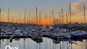 Un port de plaisance où de nombreux bateaux sont amarrés au coucher du soleil.