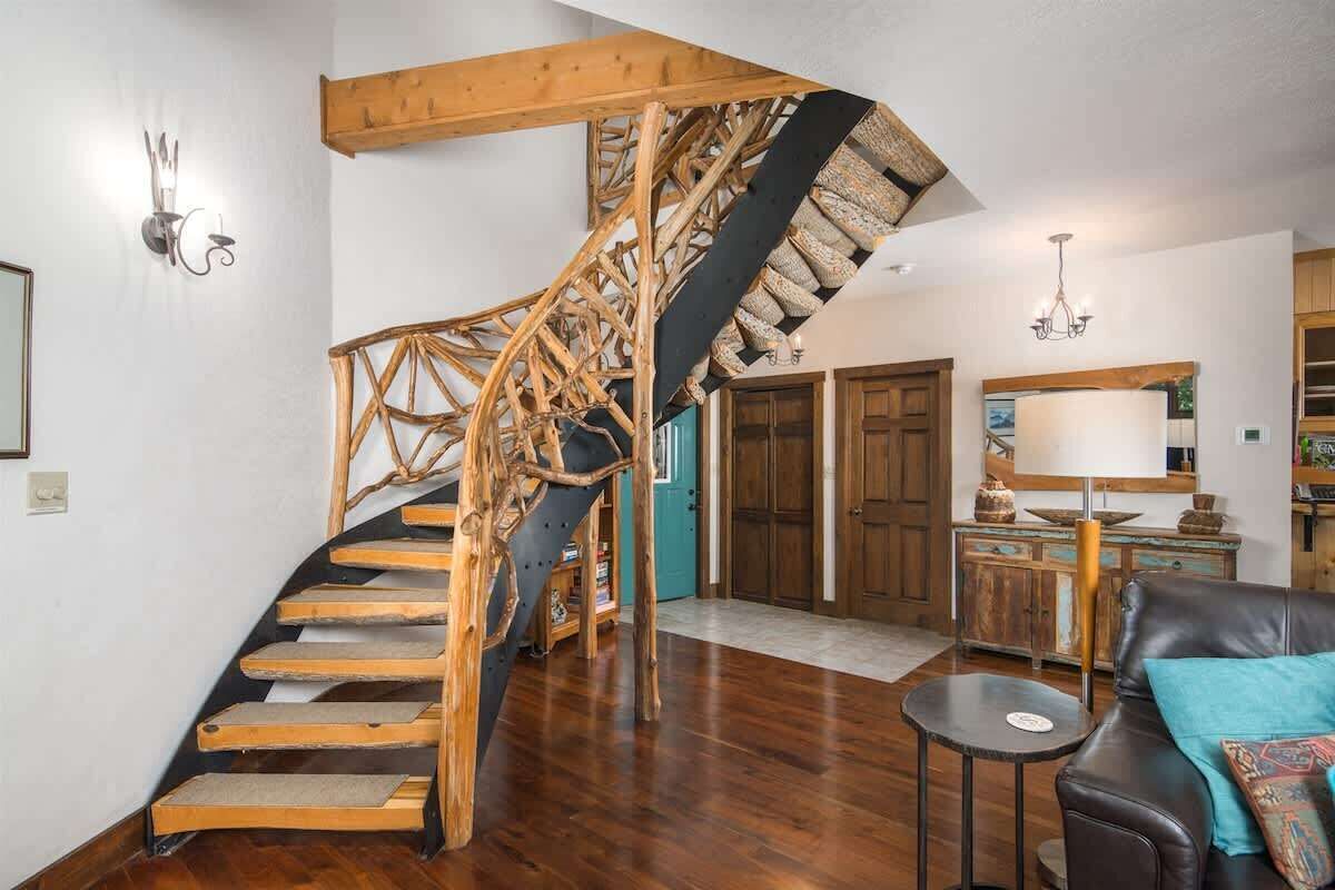 Eine Wendeltreppe mit Holzboden und einem schwarzen Geländer, die zu einer Holztür führt.