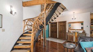 A spiral staircase with wooden steps and a black handrail, leading to a wooden door.