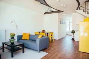 A modern living room with a grey sofa, yellow chairs, a black coffee table, and a yellow refrigerator. - Fantastic Loft with Balcony (Berlin)