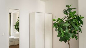 Ein weißer Kleiderschrank mit Spiegel darüber und einer Zimmerpflanze daneben.