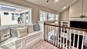 A spacious living area with a built-in bench, large windows, a fireplace, and a ceiling fan.