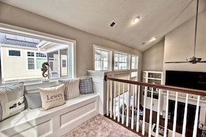 A spacious living area with a built-in bench, large windows, a fireplace, and a ceiling fan.