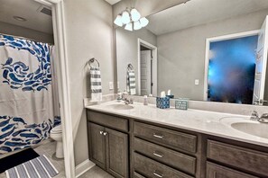 A bathroom with a double sink, a large mirror, a shower curtain with a blue whale pattern, and a sign on the counter. - Coastal Club * 5 BR w 2.5 Bath Beach House (Lewes)