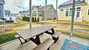 A covered patio with a picnic table and benches, overlooking a residential area with houses.