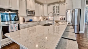 A modern kitchen with white cabinetry, stainless steel appliances, and a large island.