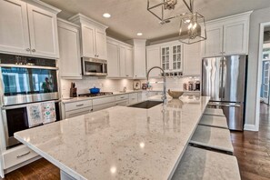 A modern kitchen with white cabinetry, stainless steel appliances, and a large island.