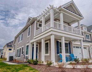 A two-story residential building with a covered porch, a garage, and a well-maintained lawn. - Coastal Club * 5 BR w 2.5 Bath Beach House (Lewes)