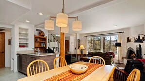 A spacious living area with a dining table, chairs, and a fireplace. - Fort Marcy 24 | Walk to Plaza | Kiva Fireplace | Full Kitchen | Hot Tub | Pool | 2 Levels (Santa Fe)