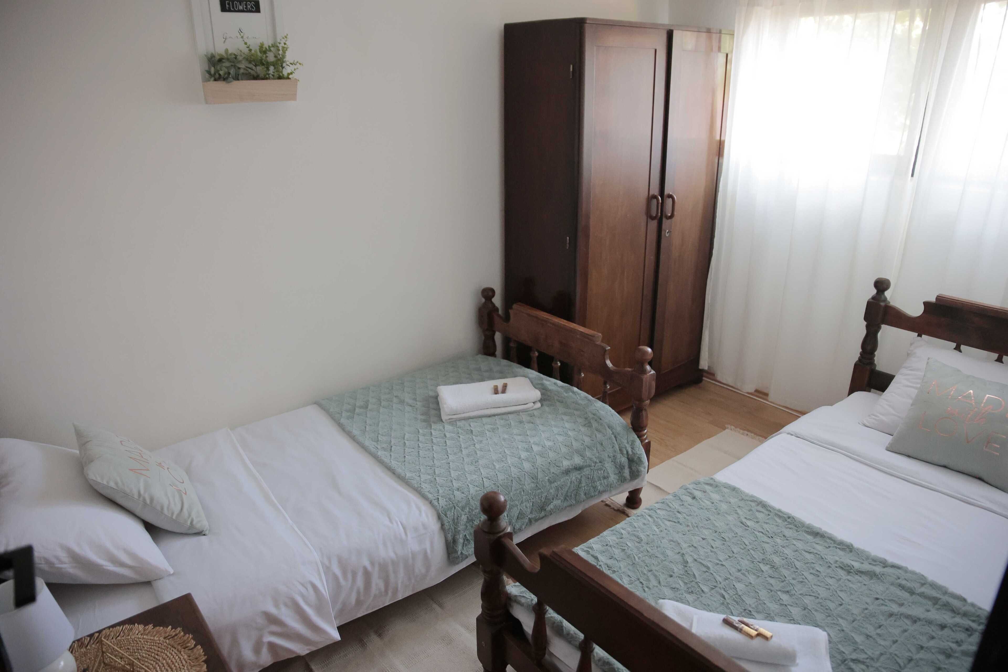 Ein Schlafzimmer mit zwei Einzelbetten, einem Holzschrank und einem kleinen Regal mit einer Pflanze.
