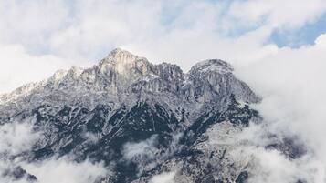 Ein Gebirgszug mit schneebedeckten Gipfeln und darunter liegenden Wolken.