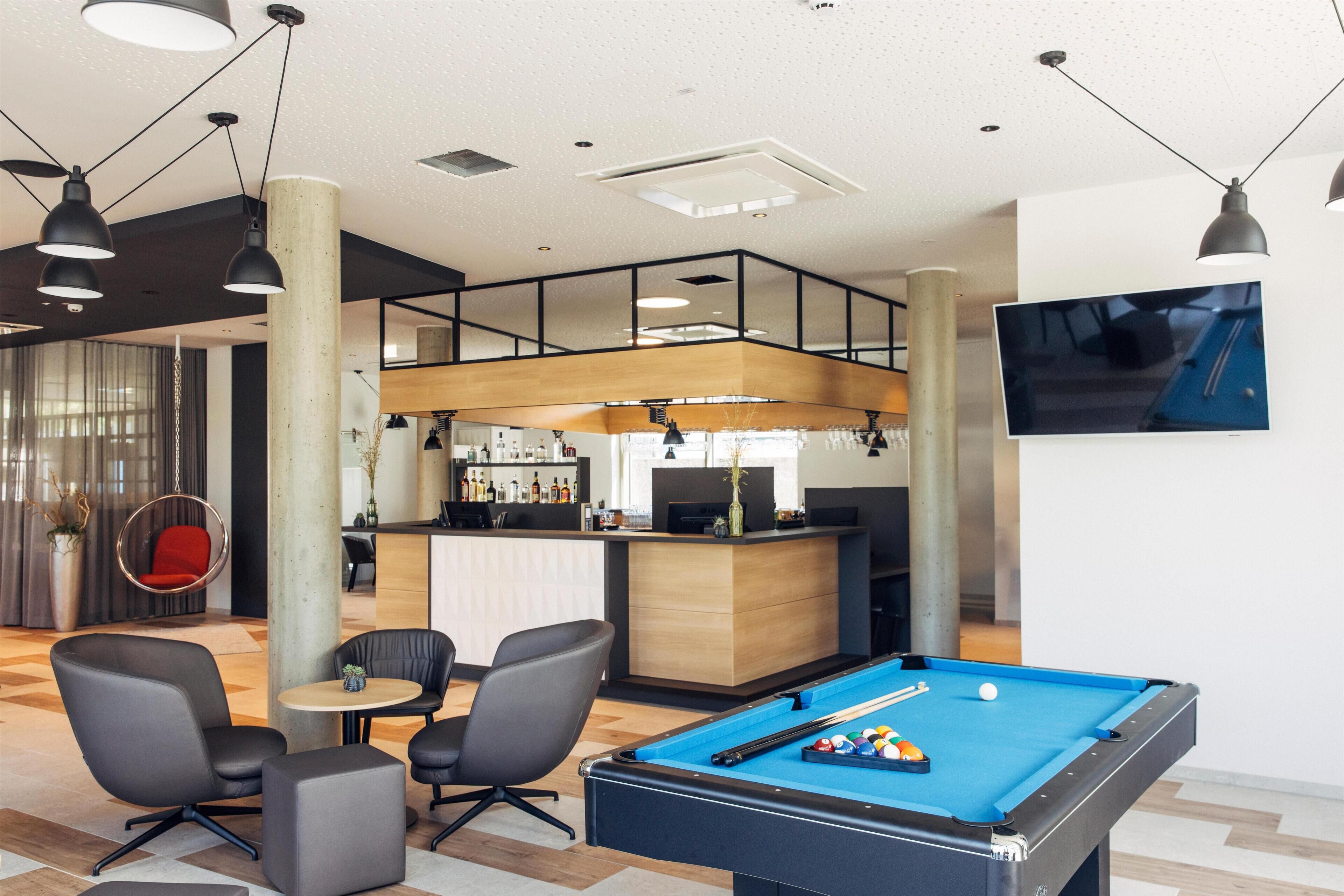 A pool table in a modern lounge area with a bar and seating.