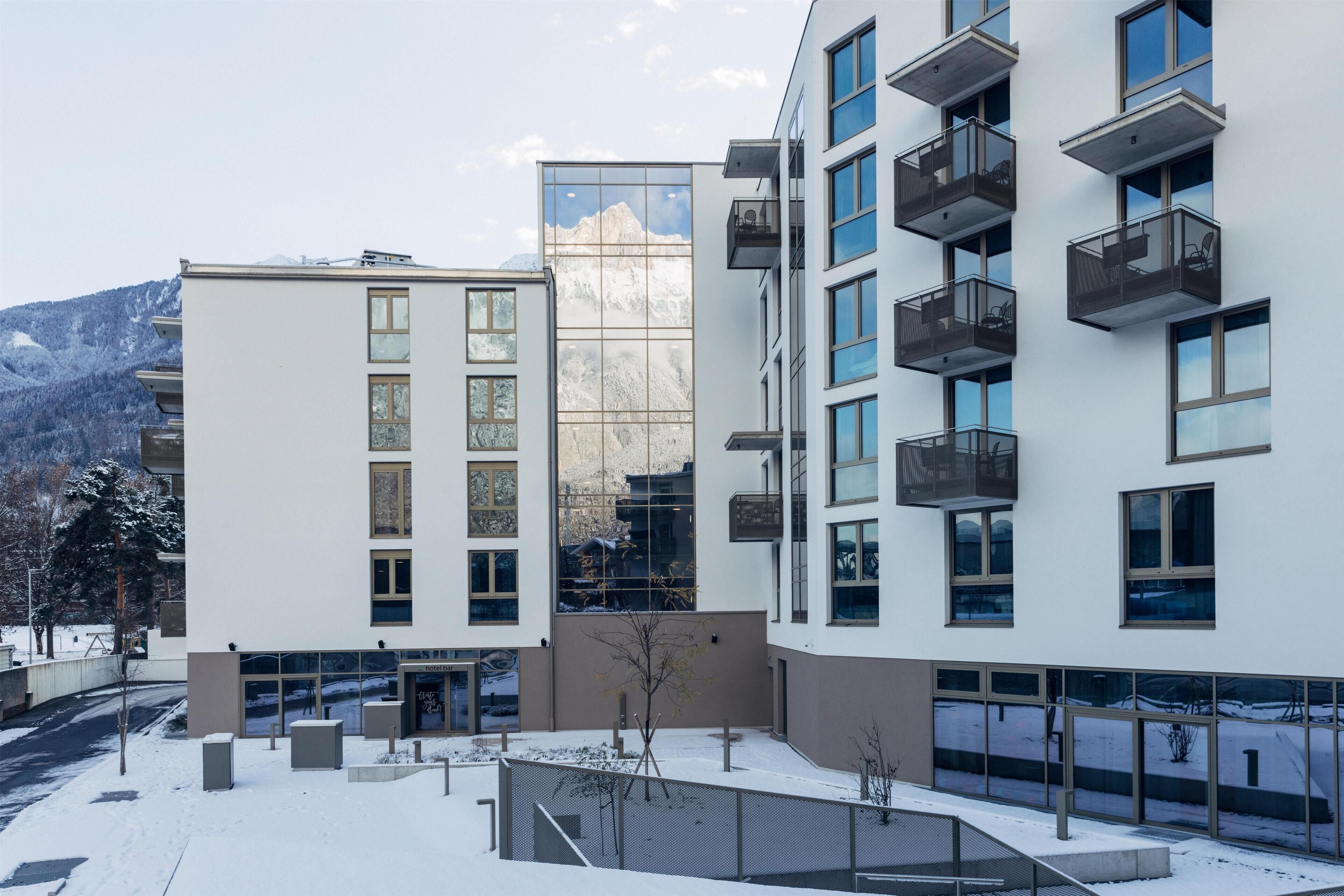 Een modern gebouw met meerdere balkons en grote ramen, omgeven door sneeuw.