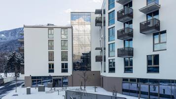 Een modern gebouw met meerdere balkons en grote ramen, omgeven door sneeuw.