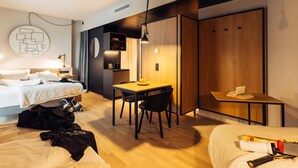 Et moderne hotelværelse med seng, skrivebord og et lille tekøkken.