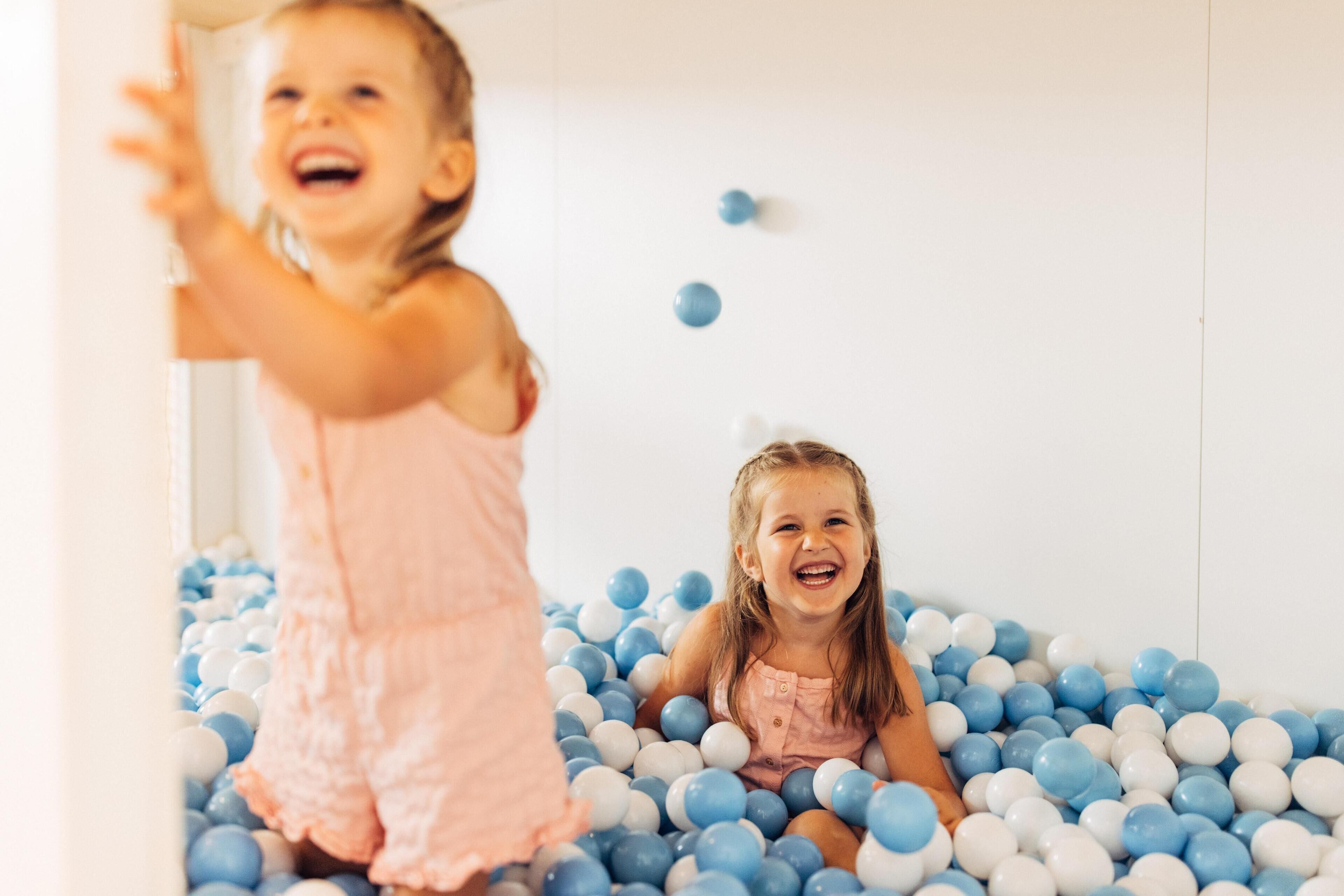 Un enfant joue dans une piscine à balles remplie de balles bleues et blanches.