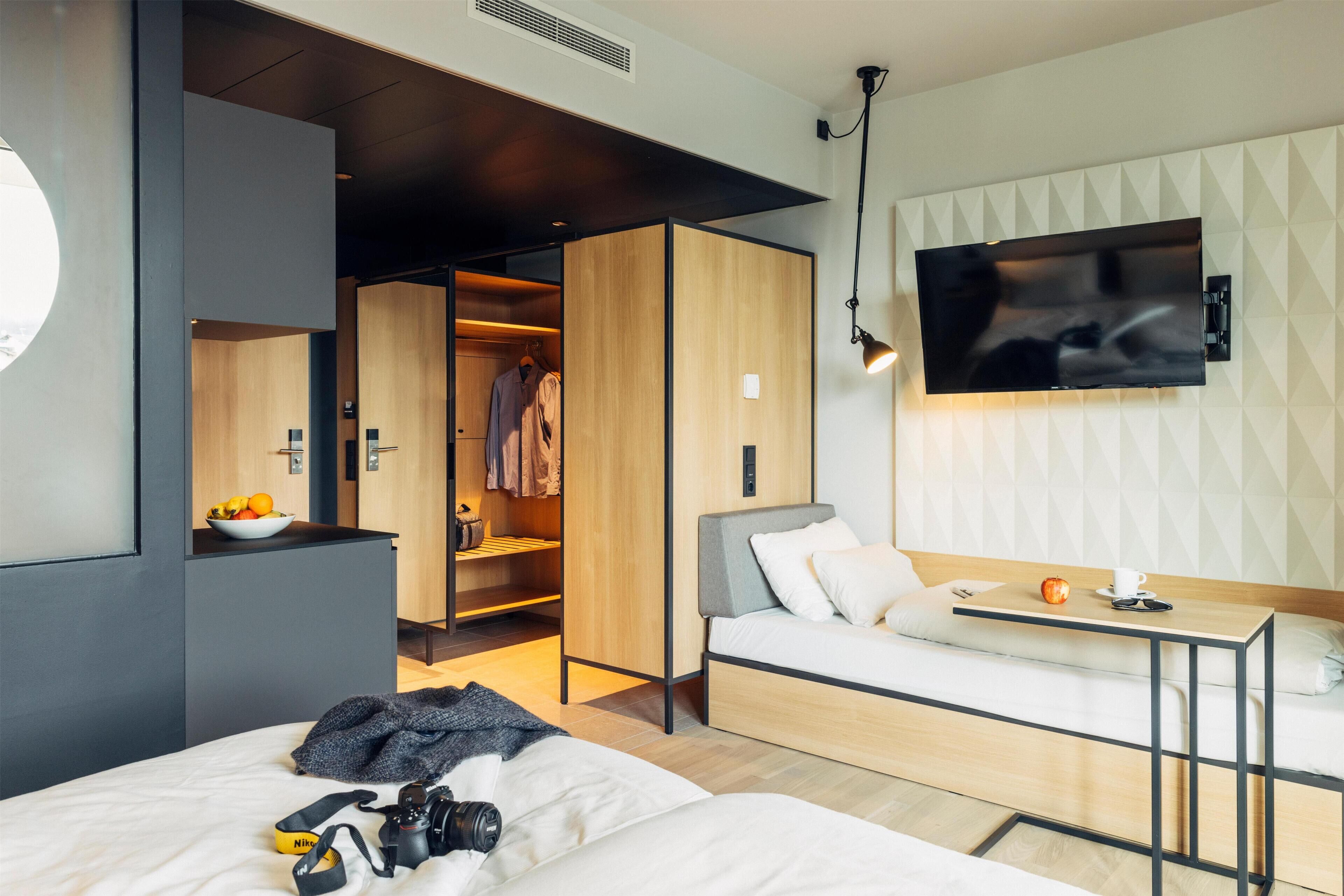 Ein modernes Hotelzimmer mit Bett, Schreibtisch, Fernseher und Kleiderschrank.