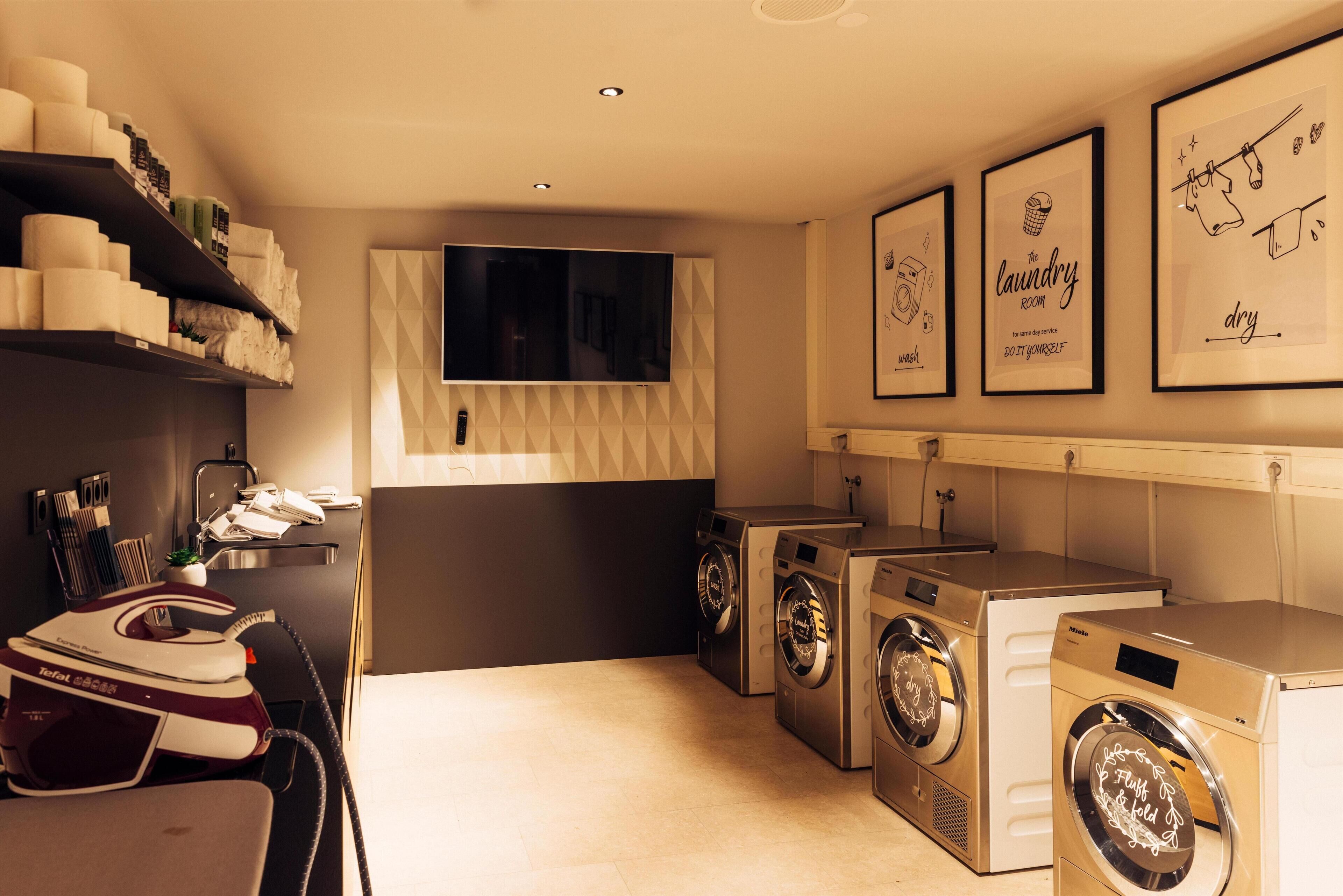 A laundry room with a washing machine, dryer, and ironing station.