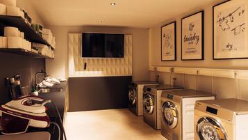 A laundry room with a washing machine, dryer, and ironing station.