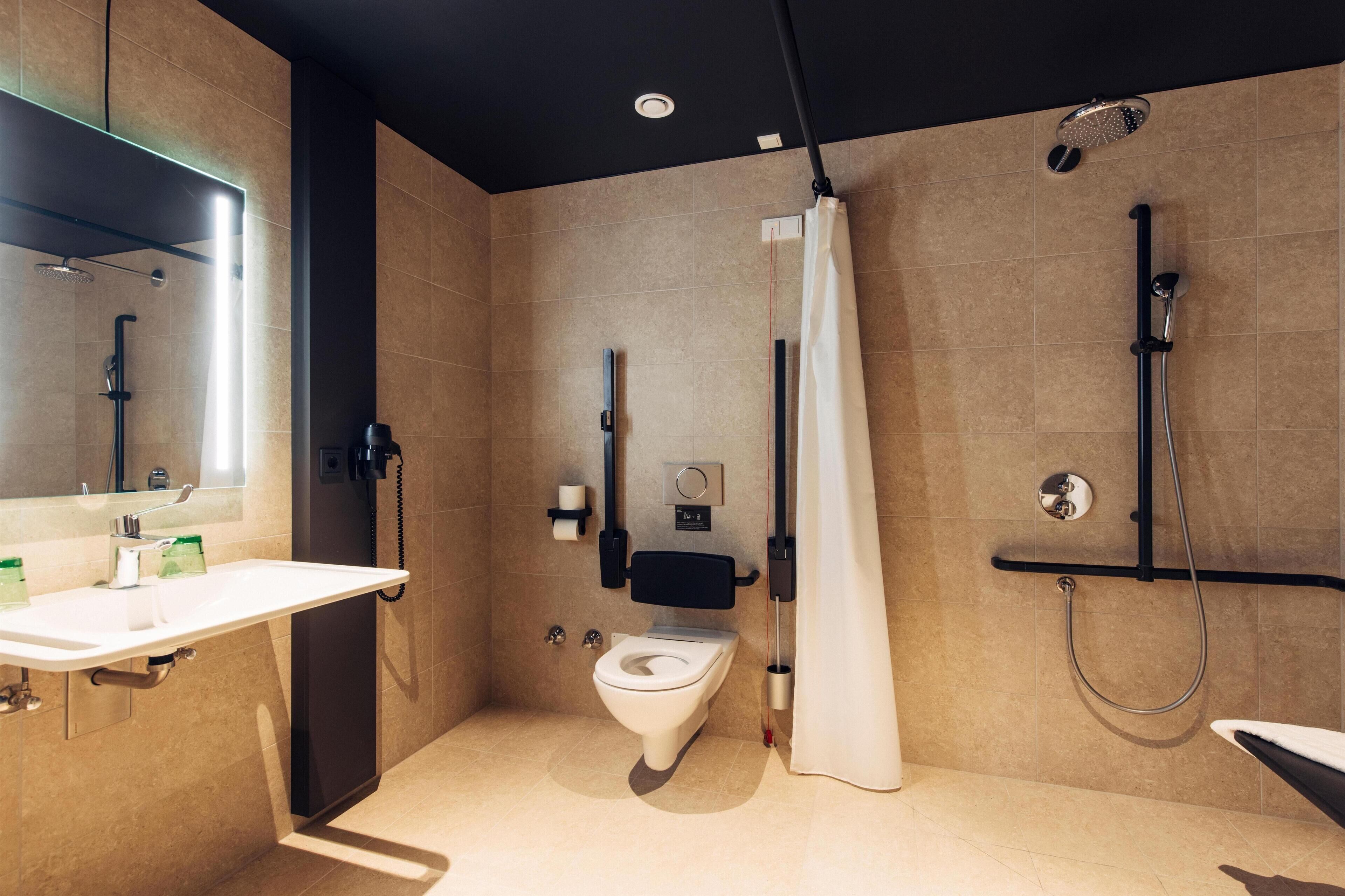 Une salle de bain moderne équipée de toilettes, d’un lavabo, d’une douche et d’un miroir.