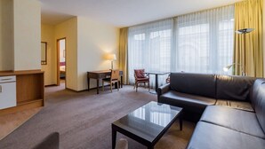 Et hotelværelse med opholdsområde, skrivebord, sofa og spisebord.